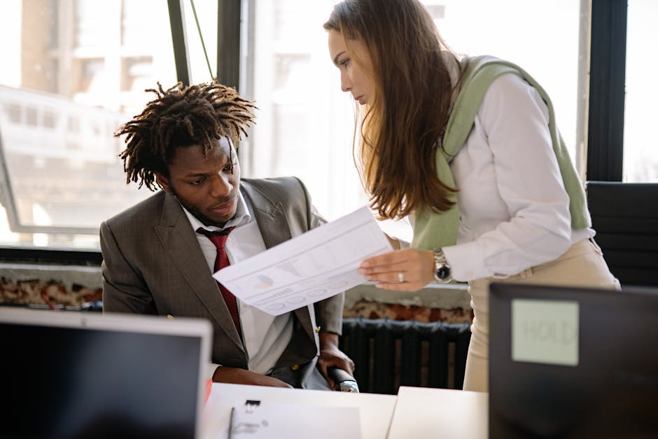 Business professionals in a discussion, reviewing documents in a modern office setting.
